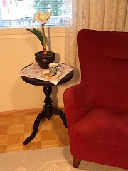 Nojatuoli ja pieni pöytä, jolla kahvikuppi piparien kera.